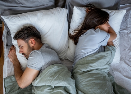 angry couple lying in bed back to back